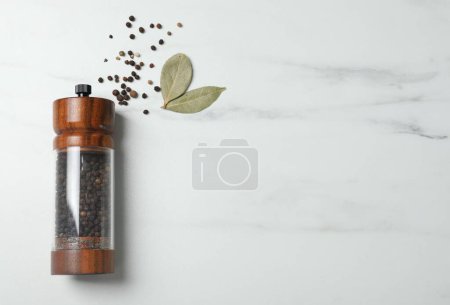 Photo for Pepper shaker and bay leaves on white marble table, flat lay. Space for text - Royalty Free Image