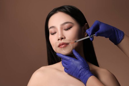 Photo for Woman getting lip injection on brown background - Royalty Free Image