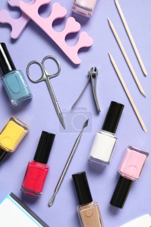 Téléchargez les photos : Vernis à ongles et ensemble d'outils de pédicure sur fond lilas, pose plate - en image libre de droit