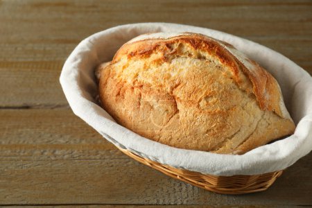 Basket with fresh bread on wooden table