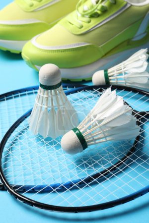 Photo for Feather badminton shuttlecocks, rackets and sneakers on light blue background, closeup - Royalty Free Image