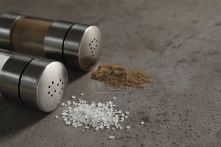 Photo for Salt and pepper shakers on grey textured table, closeup. Space for text - Royalty Free Image