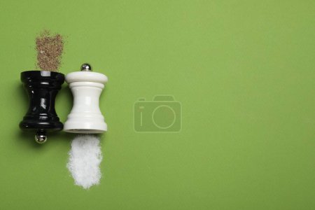 Photo for Salt and pepper shakers on green table, flat lay. Space for text - Royalty Free Image