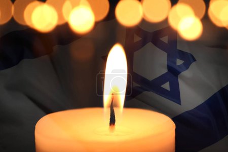 Holocaust-Gedenktag. Doppelbelichtung brennender Kerze und Flagge Israels
