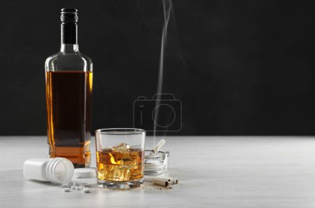 Alkohol- und Drogensucht. Whiskey im Glas, Flasche, Zigaretten und Tabletten auf weißem Tisch, Platz für Text