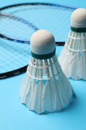 Photo for Feather badminton shuttlecocks and rackets on light blue background, closeup - Royalty Free Image