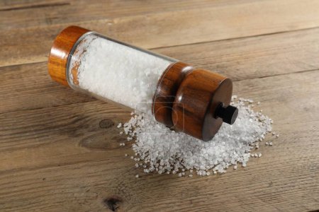 Photo for Shaker with salt on wooden table, closeup - Royalty Free Image