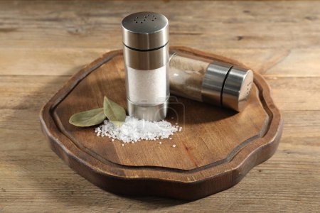 Photo for Salt and pepper shakers with bay leaves on wooden table - Royalty Free Image