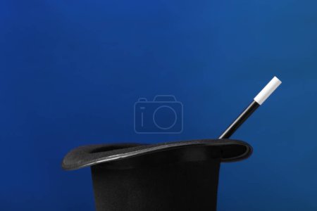 Magician's hat and wand on blue background, space for text