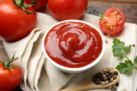 Photo for Delicious ketchup in bowl, tomatoes, parsley and peppercorns on table, closeup - Royalty Free Image