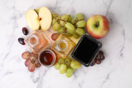 Different types of vinegar and ingredients on light marble table, flat lay