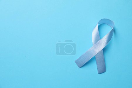 International Psoriasis Day. Ribbon as symbol of support on light blue background, top view. Space for text