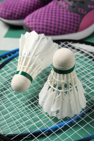 Photo for Feather badminton shuttlecocks, rackets and sneakers on court, closeup - Royalty Free Image