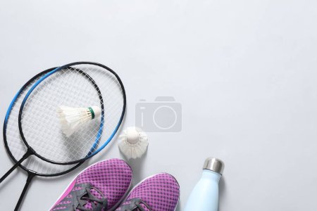 Photo for Feather badminton shuttlecocks, rackets, sneakers and bottle on gray background, flat lay. Space for text - Royalty Free Image