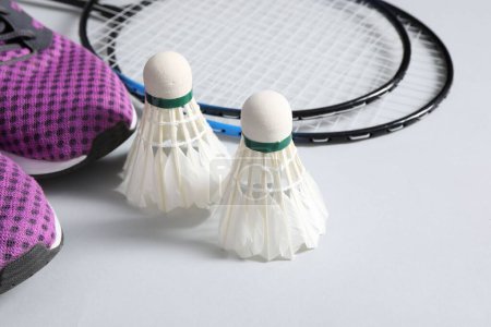 Photo for Feather badminton shuttlecocks, rackets and sneakers on gray background - Royalty Free Image