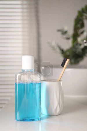Foto de Botella de enjuague bucal y cepillo de dientes en la encimera blanca en el baño - Imagen libre de derechos