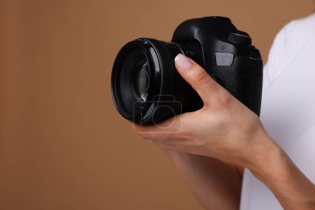 Photographer with camera on brown background, closeup. Space for text