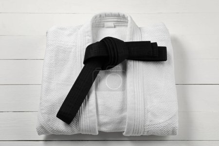 Photo for Black karate belt and white kimono on wooden background, top view - Royalty Free Image