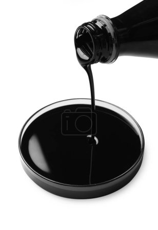 Téléchargez les photos : Verser du pétrole brut noir dans une boîte de Pétri sur fond blanc - en image libre de droit