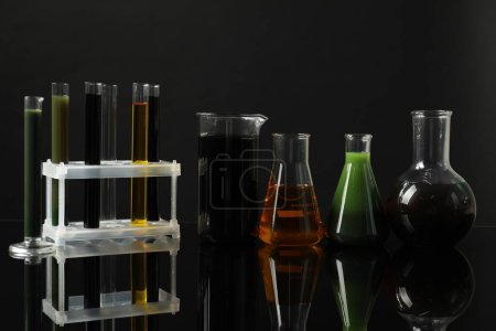 Photo for Laboratory glassware with different types of oil on black background - Royalty Free Image