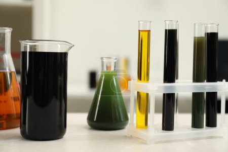 Laboratory glassware with different types of crude oil on light marble table