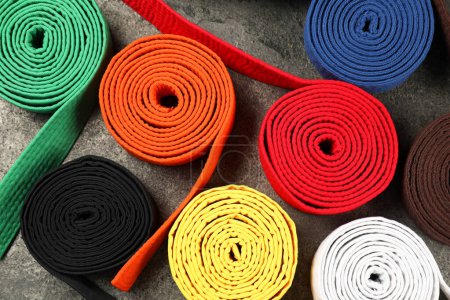 Colorful karate belts on gray background, flat lay