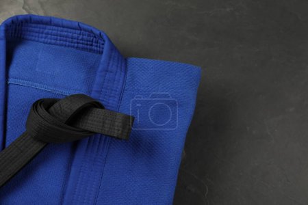 Photo for Black karate belt and blue kimono on gray background, top view. Space for text - Royalty Free Image