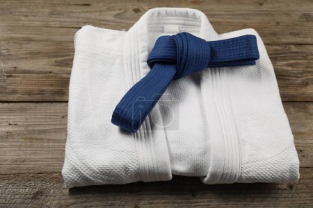 Cinturón de karate azul y kimono blanco sobre fondo de madera