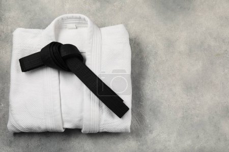 Téléchargez les photos : Ceinture de karaté noire et kimono blanc sur fond texturé gris, vue de dessus. Espace pour le texte - en image libre de droit
