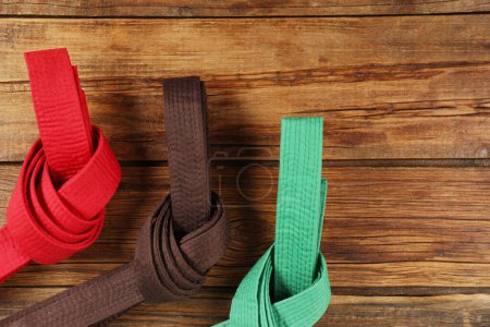 Photo for Colorful karate belts on wooden background, flat lay. Space for text - Royalty Free Image