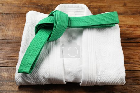 Téléchargez les photos : Ceinture de karaté vert et kimono blanc sur fond bois - en image libre de droit