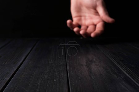 Hombre de la mano por encima de la mesa de madera negro, enfoque selectivo. Espacio para texto