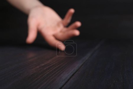 Woman holding hand above black wooden table, selective focus. Space for text