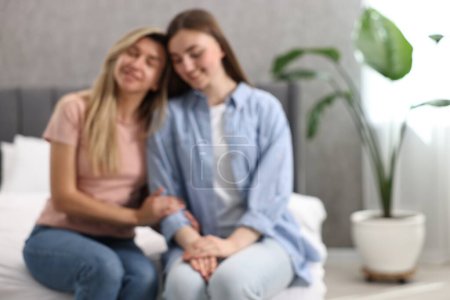 Téléchargez les photos : Vue floue de jeunes femmes heureuses assises sur le lit à la maison, espace pour le texte - en image libre de droit