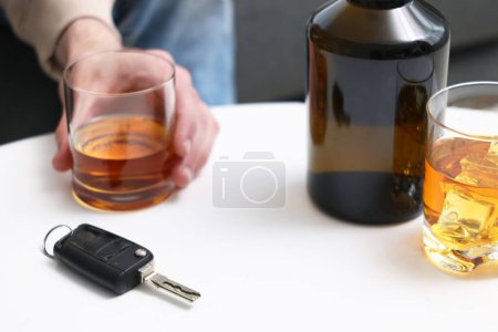 Téléchargez les photos : Homme tenant un verre de boisson alcoolisée à table avec des clés de voiture, gros plan. Ne pas boire et conduire concept - en image libre de droit
