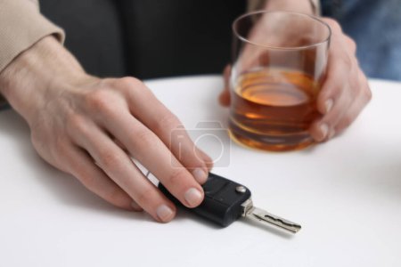 Téléchargez les photos : Homme avec verre de boisson alcoolisée et clés de voiture à table, gros plan. Ne pas boire et conduire concept - en image libre de droit