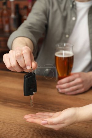Téléchargez les photos : Homme avec verre de boisson alcoolisée donnant la clé de voiture à la femme à table, gros plan. Ne pas boire et conduire concept - en image libre de droit