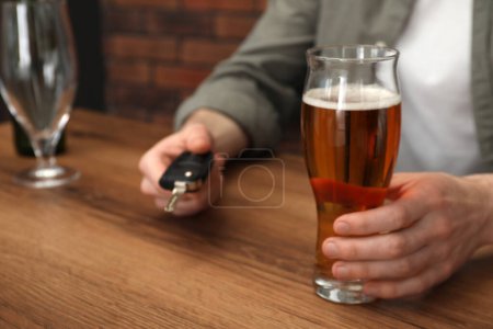 Téléchargez les photos : Homme avec un verre de boisson alcoolisée tenant la clé de voiture à table, gros plan. Ne pas boire et conduire concept - en image libre de droit