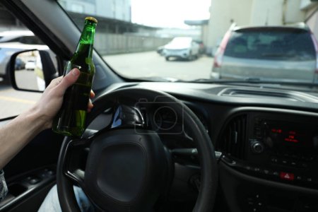 Téléchargez les photos : Homme avec une bouteille de bière voiture de conduite, gros plan. Ne pas boire et conduire concept - en image libre de droit