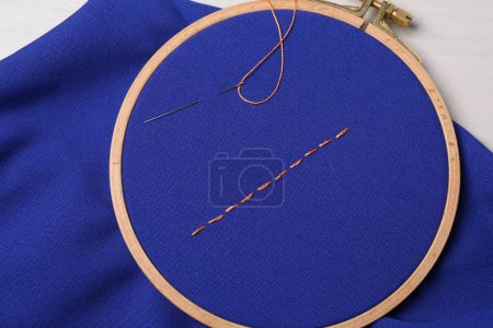 Téléchargez les photos : Tissu bleu avec points de suture, fil à coudre et aiguille sur la table, vue du dessus - en image libre de droit