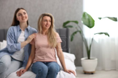 Téléchargez les photos : Vue floue de jeunes femmes heureuses assises sur le lit à la maison, espace pour le texte - en image libre de droit