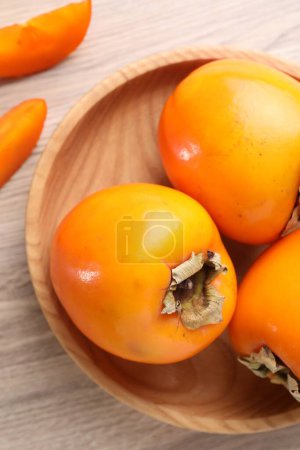 Foto de Deliciosos caquis maduros sobre mesa de madera clara, vista superior - Imagen libre de derechos