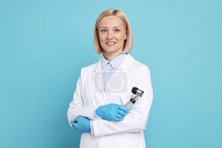 Téléchargez les photos : Happy dermatologist with dermatoscope on light blue background - en image libre de droit