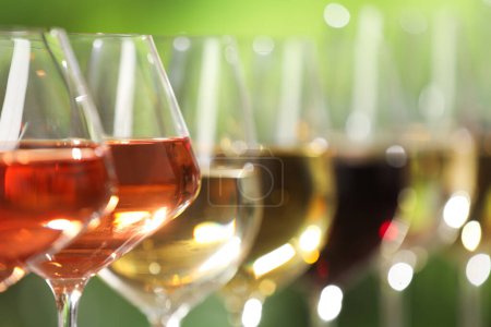 Photo for Different tasty wines in glasses against blurred background, closeup. Space for text - Royalty Free Image