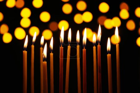Téléchargez les photos : Beaucoup de bougies d'église brûlantes dans l'obscurité, effet bokeh - en image libre de droit