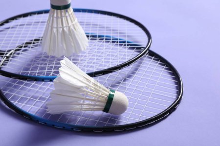 Photo for Feather badminton shuttlecocks and rackets on violet background, closeup - Royalty Free Image