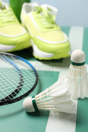 Photo for Feather badminton shuttlecocks, rackets and sneakers on court, closeup - Royalty Free Image