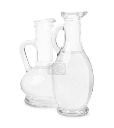 Vinagre en jarras de vidrio aisladas en blanco