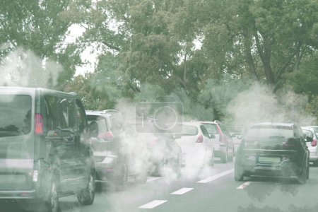Environmental pollution. Air contaminated with fumes in city. Cars surrounded by exhaust on road