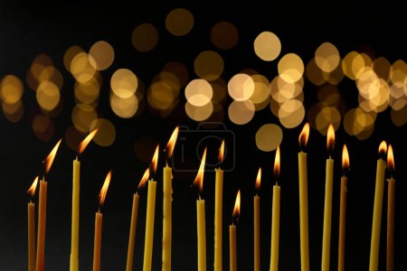 Téléchargez les photos : Beaucoup de bougies d'église brûlantes dans l'obscurité, effet bokeh - en image libre de droit